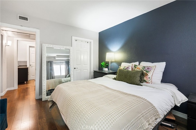 bedroom featuring visible vents, baseboards, and wood finished floors