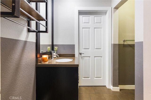 bathroom with tile patterned floors, vanity, and a textured wall