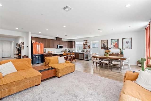 living area featuring light wood-type flooring, visible vents, and recessed lighting