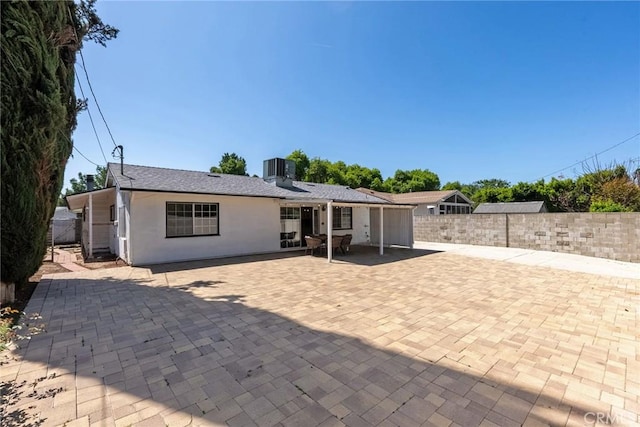 back of house featuring stucco siding, fence, central AC unit, and a patio