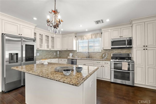 kitchen featuring appliances with stainless steel finishes, a sink, visible vents, a notable chandelier, and dark wood-type flooring