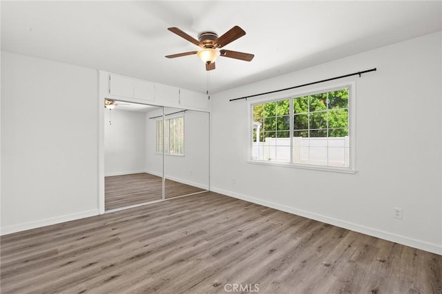 unfurnished bedroom with baseboards, ceiling fan, a closet, and light wood finished floors