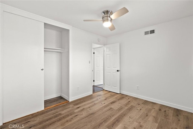 unfurnished bedroom featuring a closet, visible vents, wood finished floors, and baseboards