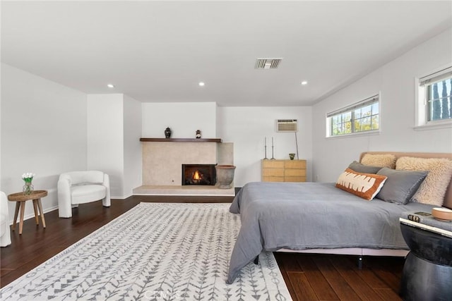bedroom with a wall mounted air conditioner, recessed lighting, hardwood / wood-style floors, and visible vents
