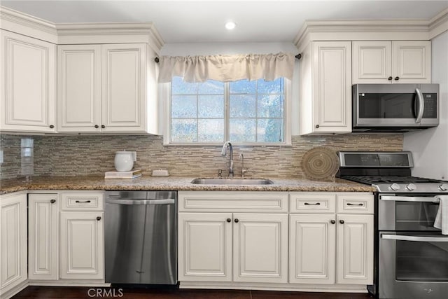 kitchen featuring light stone countertops, decorative backsplash, appliances with stainless steel finishes, white cabinets, and a sink