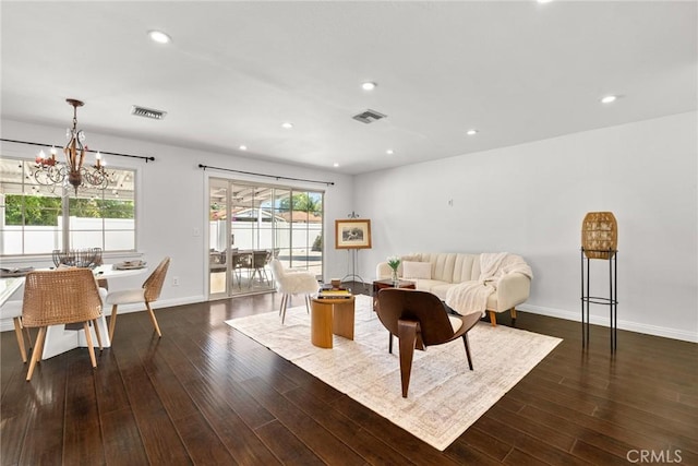 living area featuring dark wood-type flooring, a notable chandelier, and visible vents