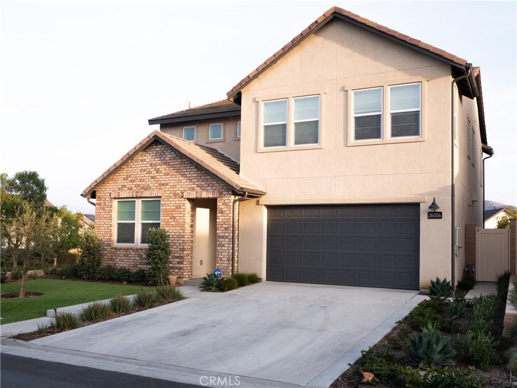 view of front facade featuring an attached garage, driveway, stucco siding, and brick siding