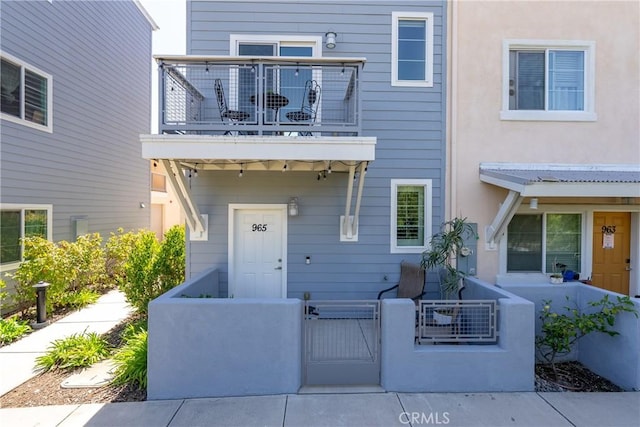 view of front facade with a balcony, a gate, and a fenced front yard
