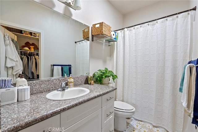 full bath with toilet, vanity, and a walk in closet