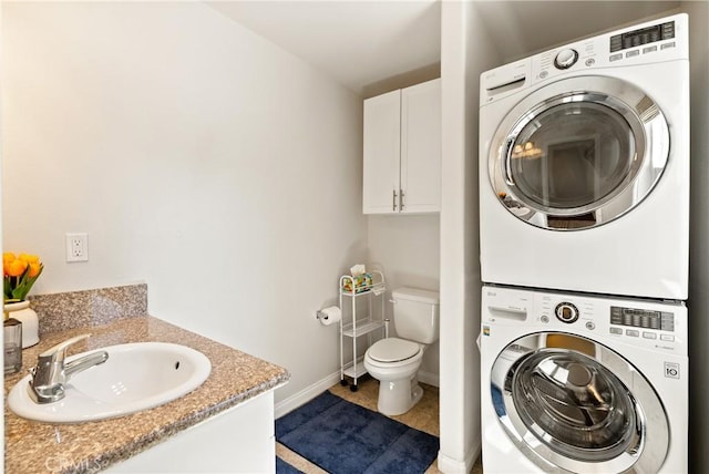 bathroom featuring vanity, baseboards, tile patterned floors, toilet, and stacked washer / drying machine