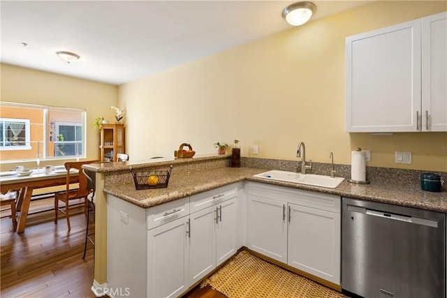 kitchen featuring a peninsula, light wood-style flooring, white cabinetry, dishwasher, and a sink