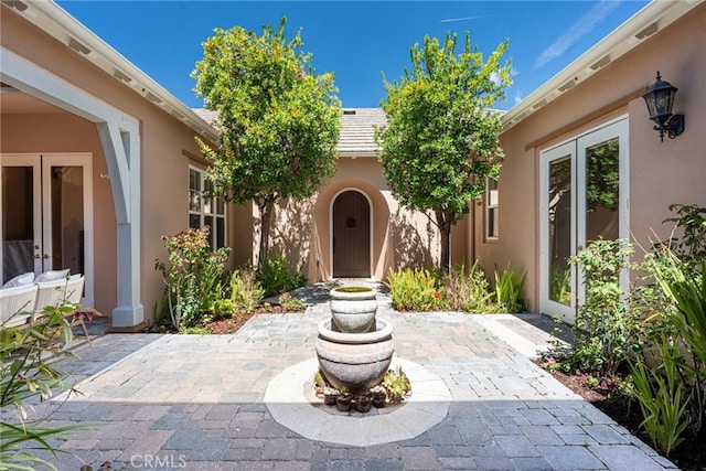 entrance to property featuring stucco siding, a patio, and french doors