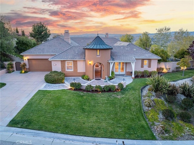 mediterranean / spanish-style house with stucco siding, an attached garage, a chimney, and fence