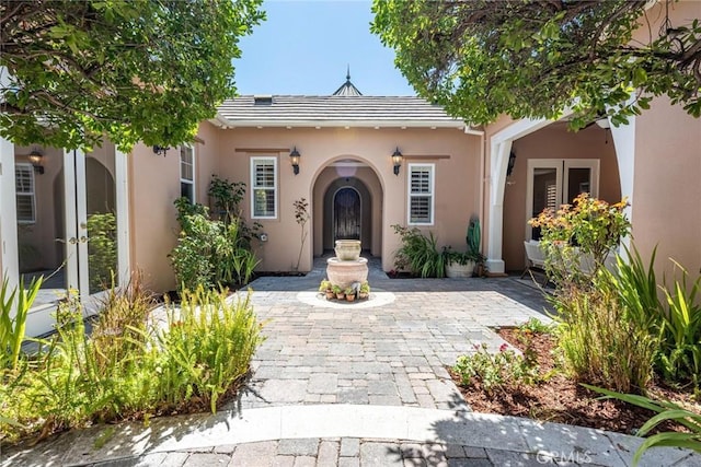 property entrance featuring stucco siding, a tiled roof, and french doors