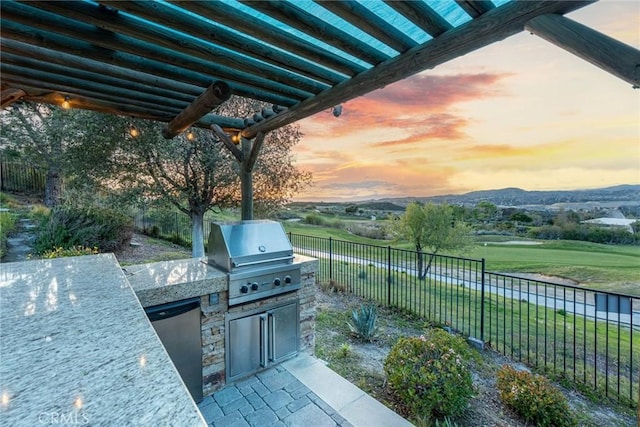 view of patio featuring exterior kitchen, a fenced backyard, area for grilling, and a mountain view