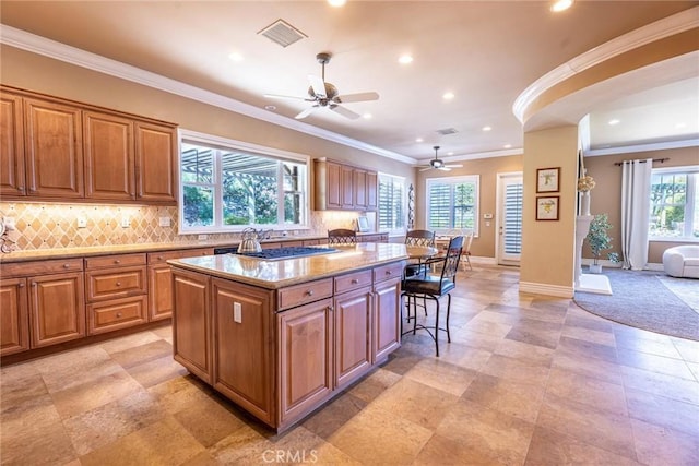 kitchen with a ceiling fan, visible vents, recessed lighting, a center island, and light stone counters