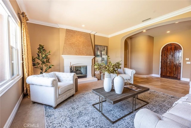 living area featuring crown molding, arched walkways, baseboards, visible vents, and recessed lighting