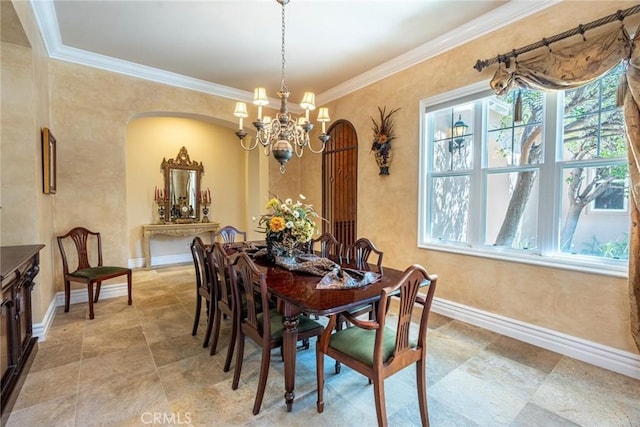 dining space featuring arched walkways, a notable chandelier, crown molding, and baseboards
