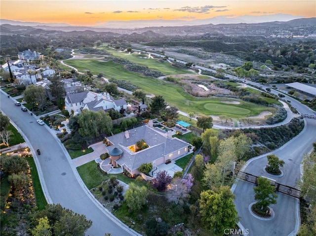 aerial view at dusk with golf course view and a mountain view