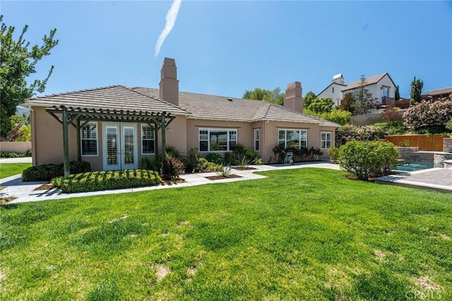 back of house featuring a pergola, french doors, a chimney, and a lawn