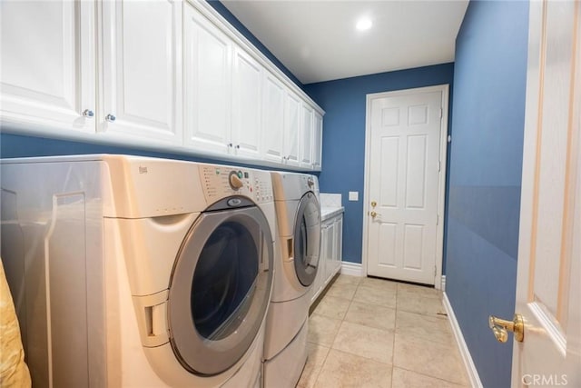 laundry area with washer and dryer, light tile patterned floors, baseboards, and cabinet space