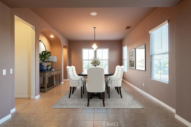 dining space with visible vents, baseboards, arched walkways, and tile patterned floors