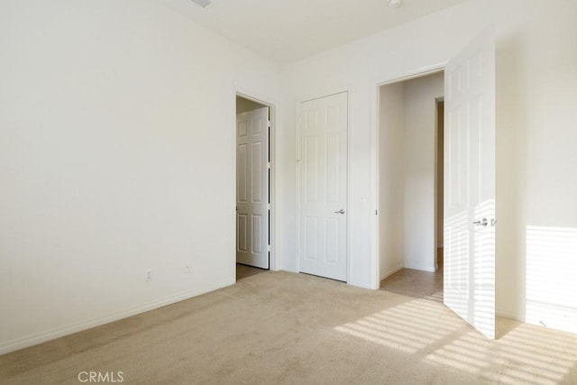 unfurnished bedroom with baseboards and light colored carpet