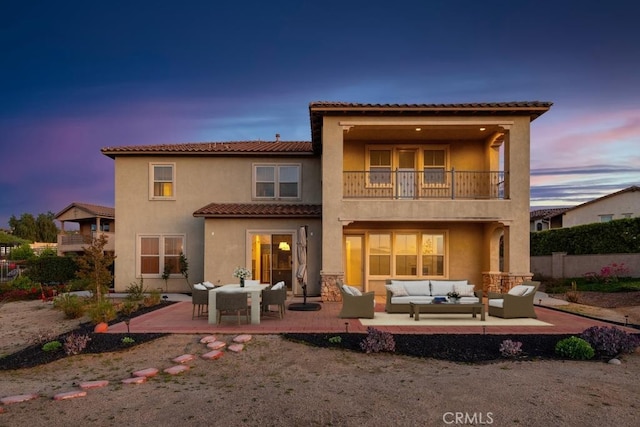 back of house featuring an outdoor hangout area, stucco siding, a patio area, and a balcony