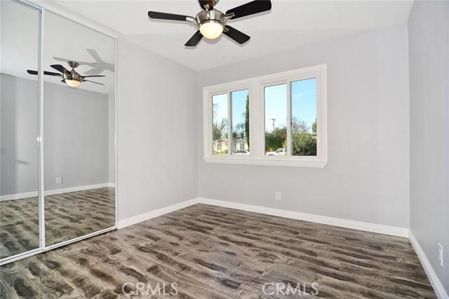 unfurnished bedroom featuring baseboards, ceiling fan, a closet, and wood finished floors