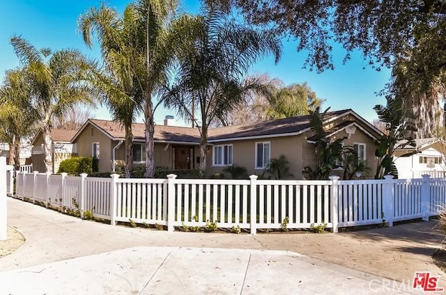 ranch-style house featuring a fenced front yard and stucco siding