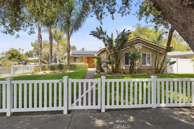 single story home with a fenced front yard, solar panels, and a front lawn