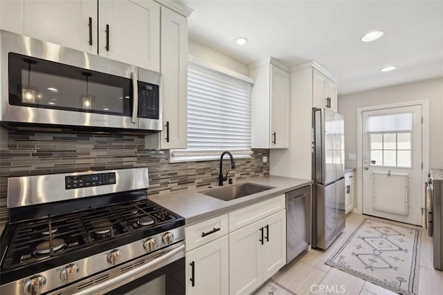 kitchen featuring white cabinets, a sink, light countertops, stainless steel appliances, and backsplash