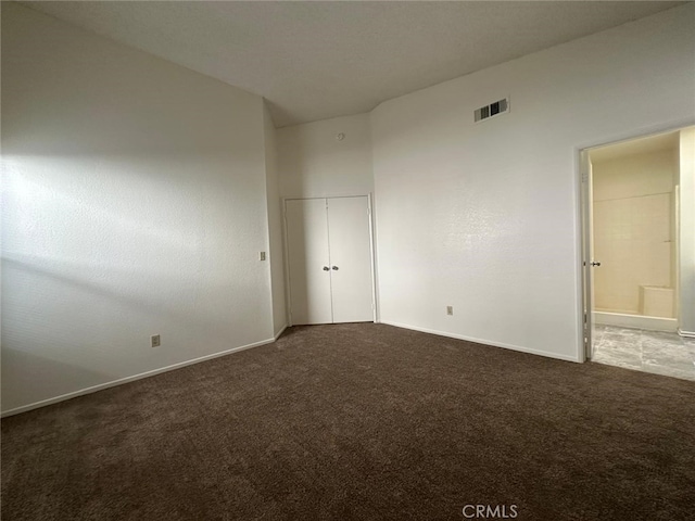 unfurnished bedroom featuring visible vents, carpet floors, ensuite bath, a closet, and baseboards