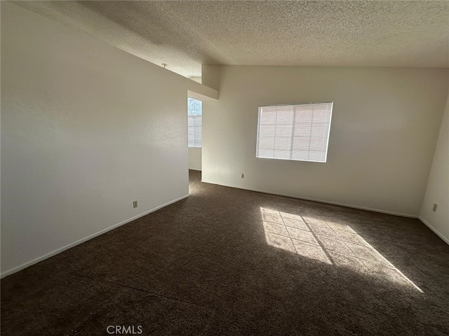 empty room with baseboards, dark carpet, and a textured ceiling
