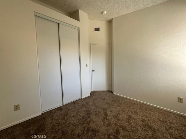 unfurnished bedroom featuring visible vents, a closet, baseboards, a textured ceiling, and carpet flooring