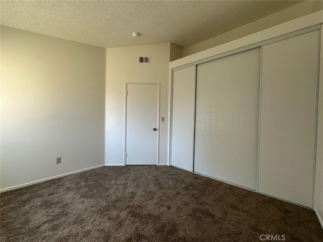 unfurnished bedroom with visible vents, a closet, baseboards, a textured ceiling, and carpet flooring