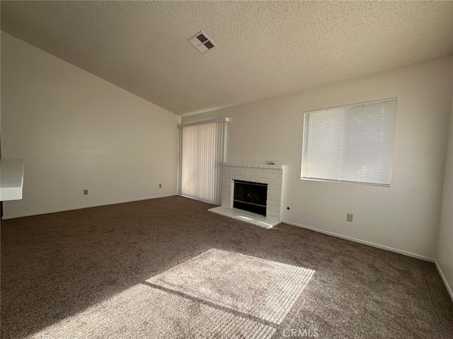 unfurnished living room with a fireplace, a textured ceiling, visible vents, and carpet
