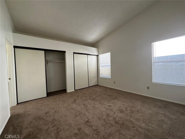 unfurnished bedroom featuring a textured ceiling, carpet, multiple closets, and baseboards