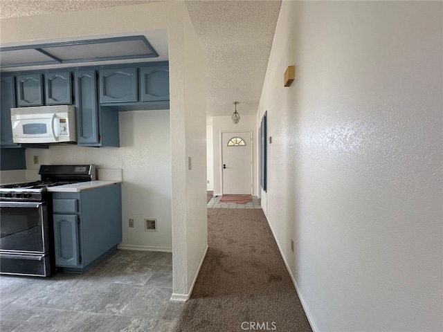 kitchen featuring light countertops, white microwave, baseboards, gas range, and a textured ceiling