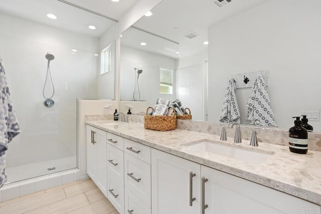 bathroom with walk in shower, double vanity, a sink, and tile patterned flooring