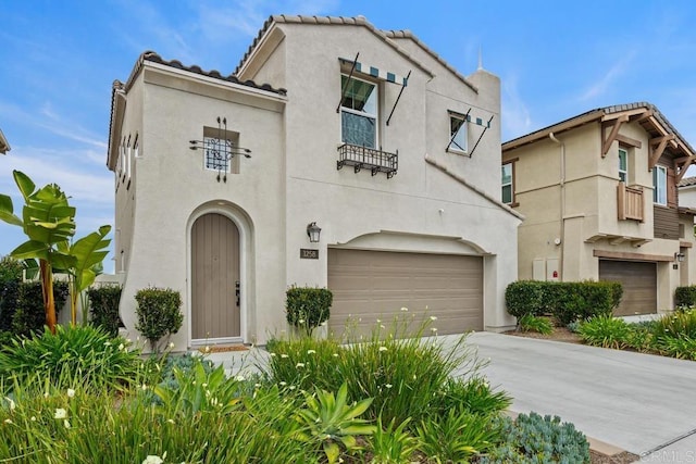 mediterranean / spanish house featuring a garage, stucco siding, and concrete driveway