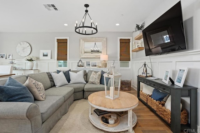 living area featuring a decorative wall, visible vents, recessed lighting, a chandelier, and light wood finished floors