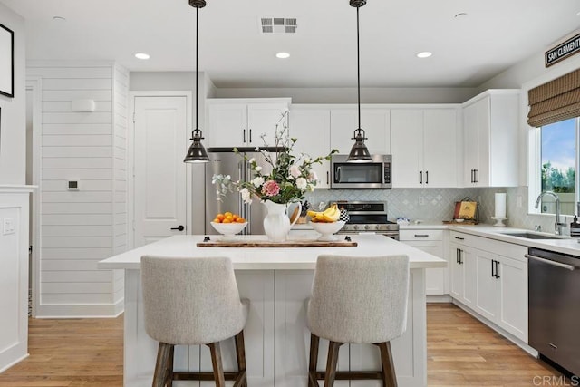 kitchen featuring a kitchen island, visible vents, a breakfast bar area, stainless steel appliances, and a sink