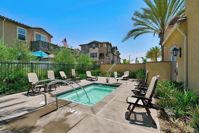 view of swimming pool featuring a community hot tub, a patio area, and fence private yard
