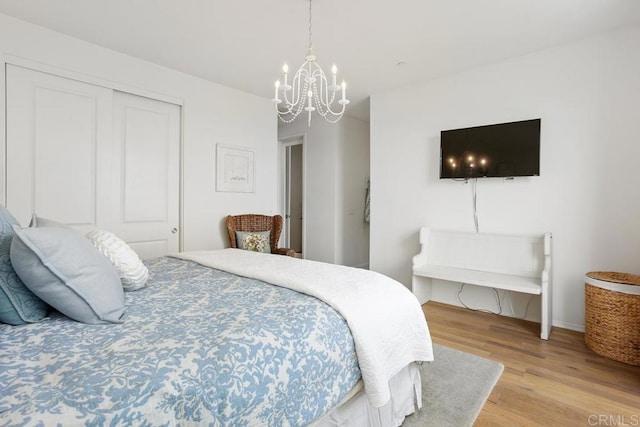bedroom with a closet, light wood-style flooring, and a notable chandelier