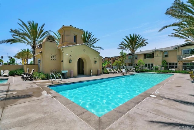 community pool featuring a patio area, fence, and a residential view