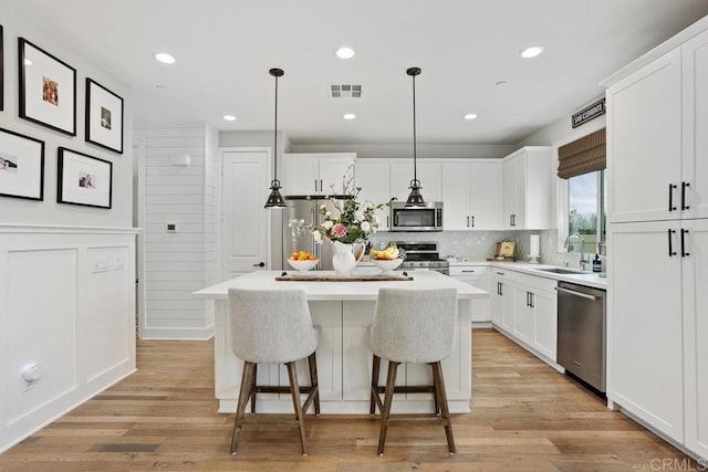 kitchen with a kitchen island, visible vents, a breakfast bar area, stainless steel appliances, and a sink