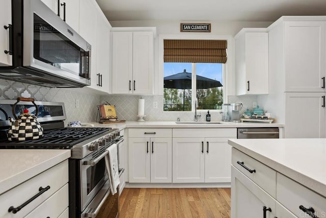 kitchen featuring light countertops, appliances with stainless steel finishes, a sink, and backsplash