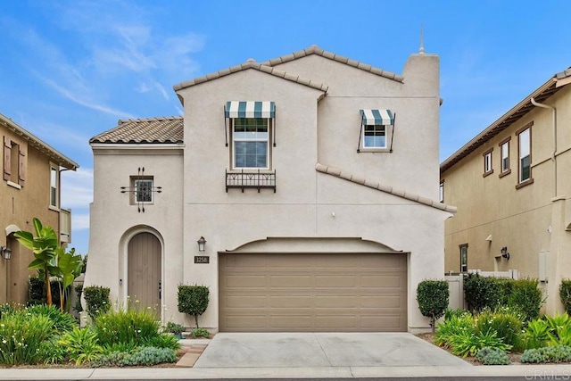 mediterranean / spanish-style house featuring an attached garage, concrete driveway, stucco siding, and a tile roof