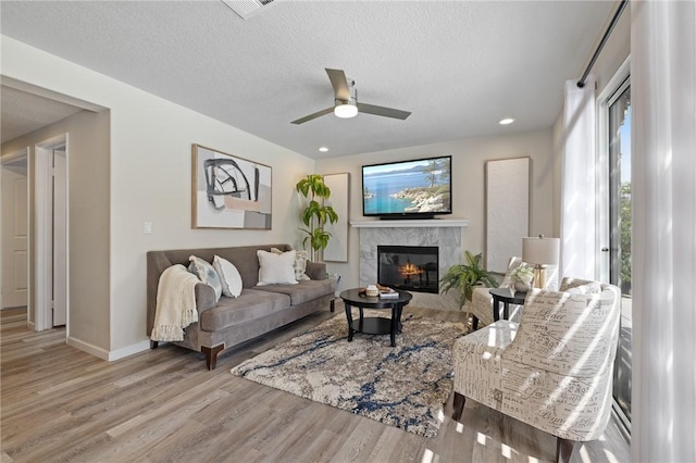 78675 Bradford Cir, La Quinta, CA 92253 - living area featuring a fireplace, a textured ceiling, a ceiling fan, wood finished floors, and baseboards